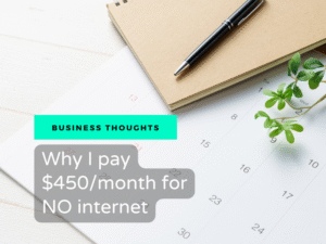 A white desk calendar with a brown notebook, a sleek black pen, and a small green leafy plant on a white wooden surface. Overlaid text on a bright teal banner reads "BUSINESS THOUGHTS" above a grey graphic with white text that reads, "Why I pay $450/month for NO internet".